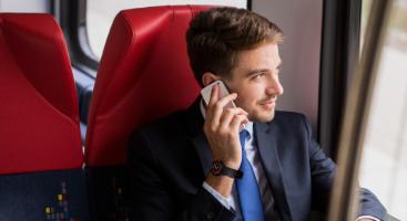 an employee in a suit talks on the phone while taking a commuter shuttle service